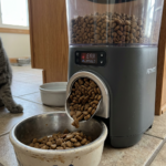 Automatic pet feeder dispensing dry cat food into a metal bowl